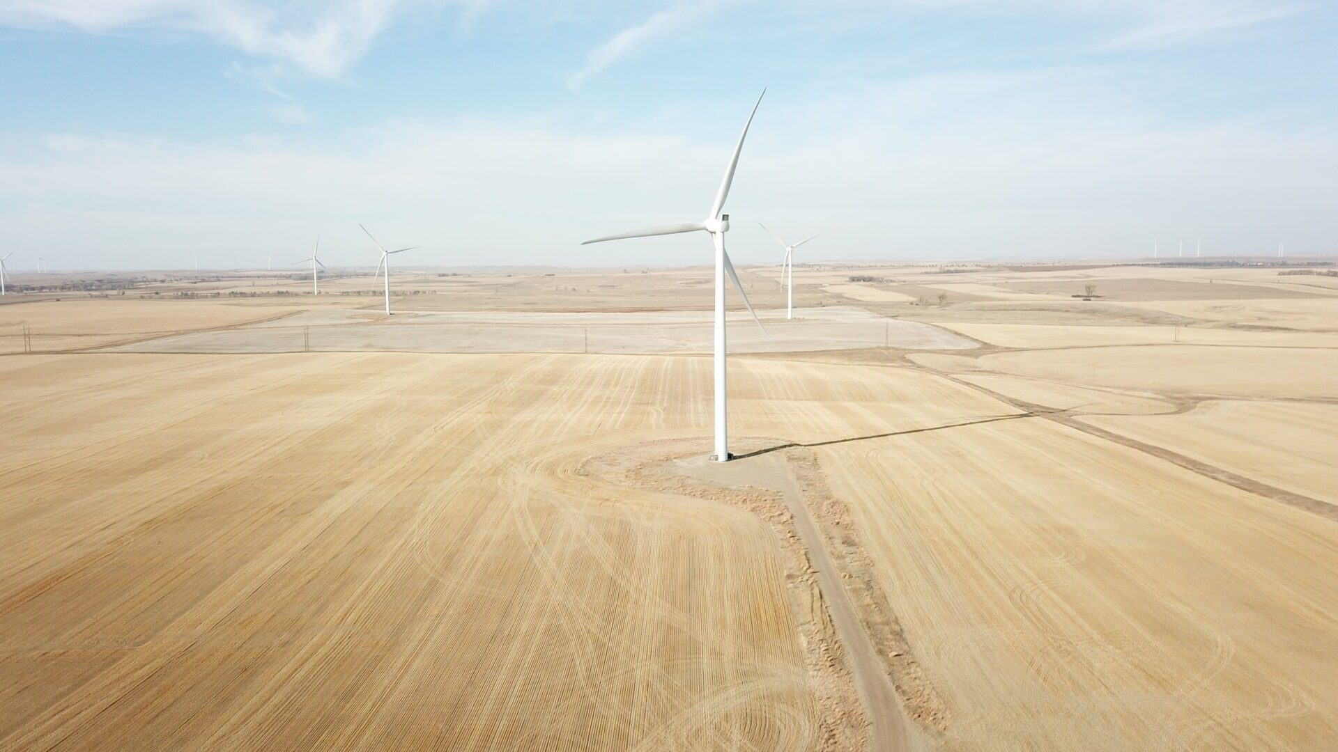 A wind turbine in the middle of an empty field.